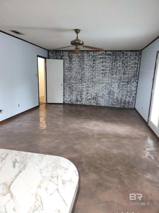 spare room with ceiling fan, a textured ceiling, and brick wall