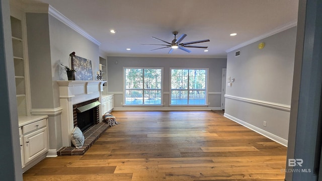 living room featuring a brick fireplace, built in features, ceiling fan, and crown molding