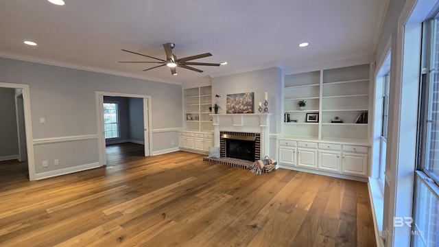 unfurnished living room featuring built in features, ornamental molding, and a brick fireplace