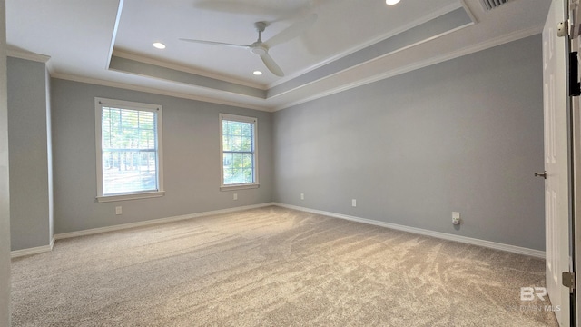 carpeted spare room with a tray ceiling, crown molding, and ceiling fan