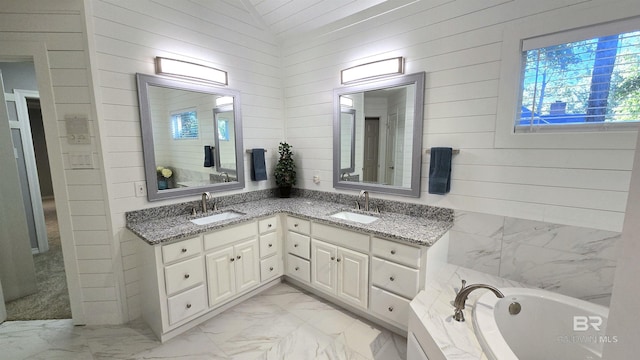 bathroom featuring vanity, a tub to relax in, vaulted ceiling, and wooden walls