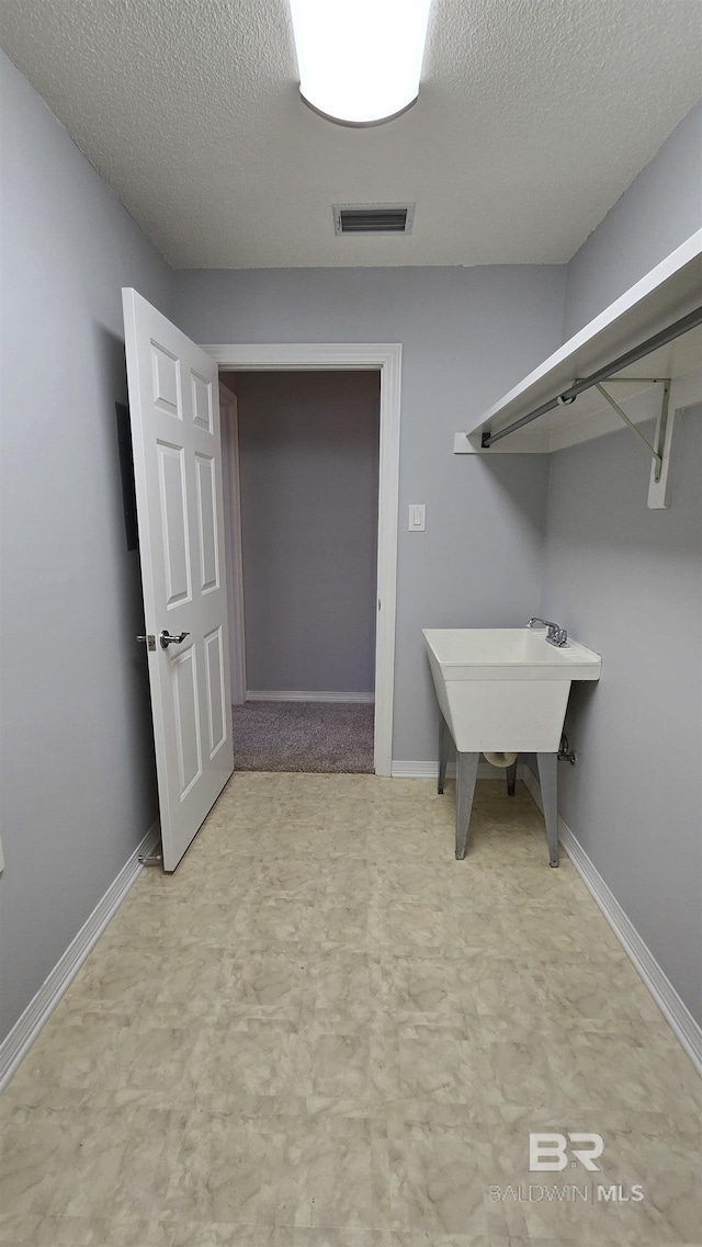 clothes washing area with a textured ceiling