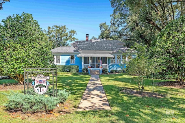 view of front facade featuring a sunroom and a front lawn