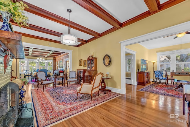 living room featuring ceiling fan with notable chandelier, beam ceiling, hardwood / wood-style floors, and a high end fireplace