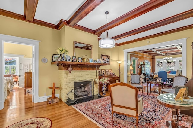 living room featuring light hardwood / wood-style flooring, crown molding, beam ceiling, and a fireplace