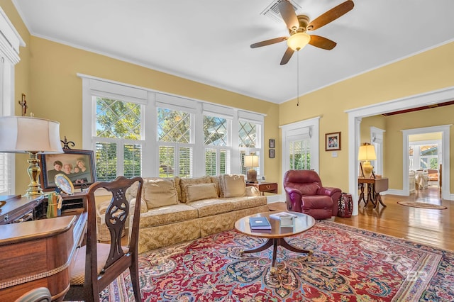 living room featuring hardwood / wood-style flooring, crown molding, ceiling fan, and a wealth of natural light