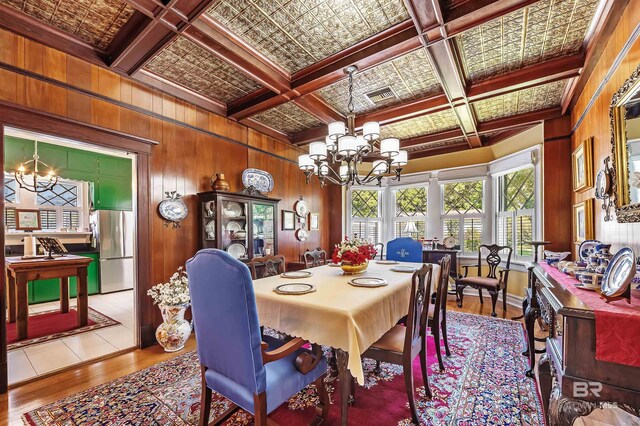 dining area featuring wooden walls, beam ceiling, coffered ceiling, and light wood-type flooring