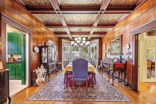 dining room with light wood-type flooring, coffered ceiling, and wooden walls