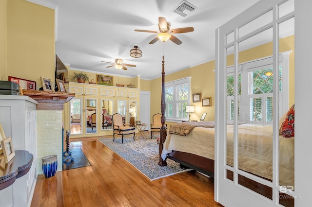 bedroom with ornamental molding, a brick fireplace, and hardwood / wood-style flooring