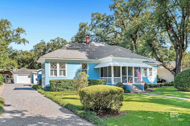 bungalow-style home featuring a sunroom, an outdoor structure, a front yard, and a garage