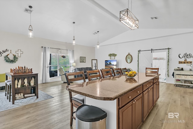kitchen featuring light wood-style floors, hanging light fixtures, visible vents, and a center island