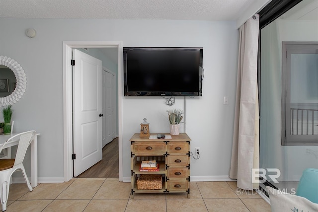 living room featuring light tile patterned floors, a textured ceiling, and baseboards