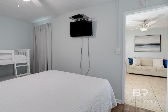 bedroom with tile patterned floors, a ceiling fan, and a textured ceiling