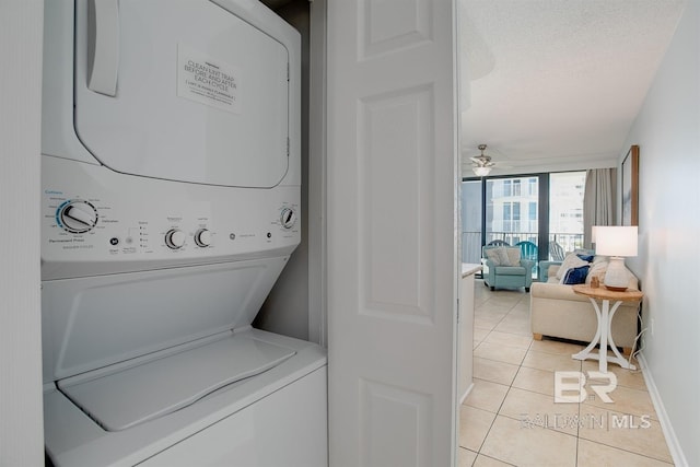 laundry room with stacked washer and dryer, a textured ceiling, light tile patterned flooring, baseboards, and laundry area