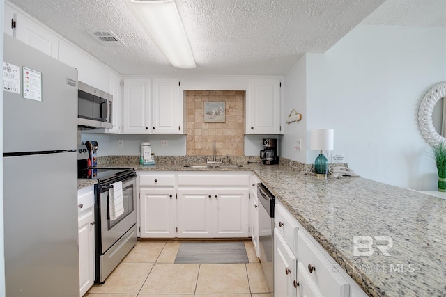 kitchen with white cabinets, light stone countertops, appliances with stainless steel finishes, and a sink