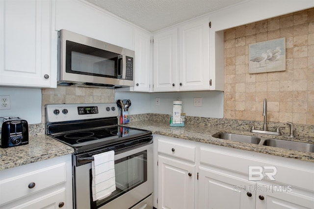 kitchen featuring a sink, stainless steel appliances, backsplash, and white cabinetry