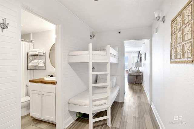 bedroom with light wood-type flooring, a sink, and baseboards