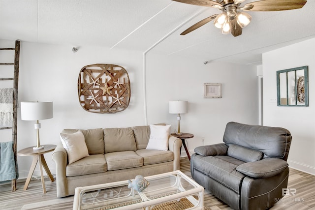 living room featuring ceiling fan, a textured ceiling, light wood-type flooring, and baseboards