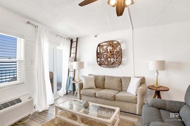 living area featuring a textured ceiling, light wood-type flooring, and a ceiling fan