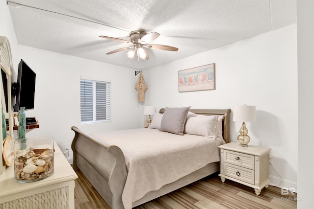 bedroom featuring light wood-style floors, baseboards, a ceiling fan, and a textured ceiling