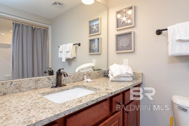 bathroom featuring toilet, a shower with shower curtain, vanity, and visible vents