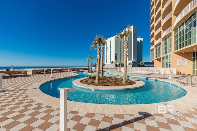 pool featuring a water view and a patio