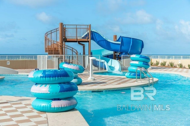 pool featuring fence, a water play area, and a water slide