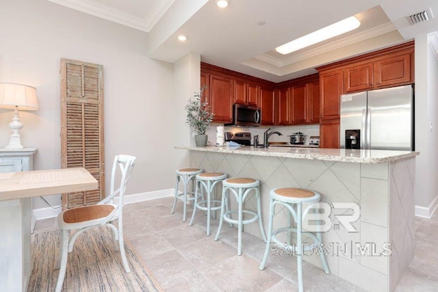 kitchen with stainless steel appliances, visible vents, ornamental molding, a kitchen breakfast bar, and baseboards