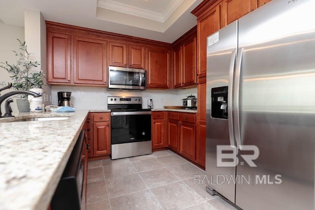 kitchen with appliances with stainless steel finishes, a sink, a tray ceiling, crown molding, and backsplash