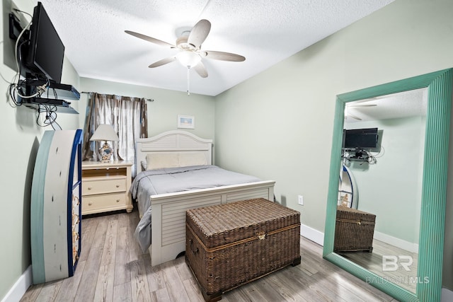 bedroom featuring light wood-type flooring, a textured ceiling, and baseboards