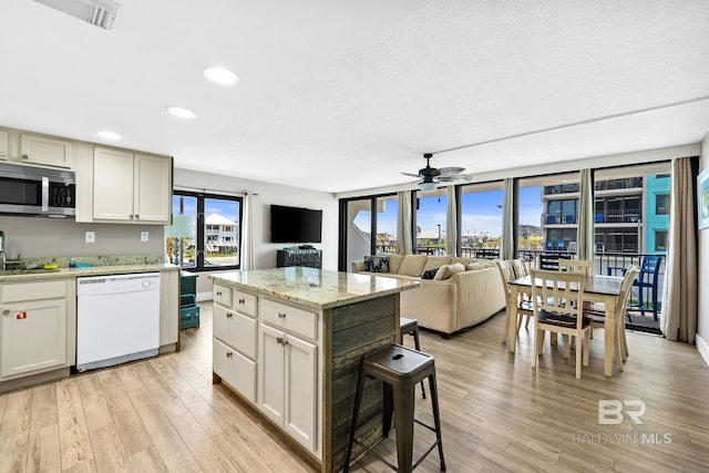 kitchen featuring visible vents, open floor plan, a center island, dishwasher, and stainless steel microwave