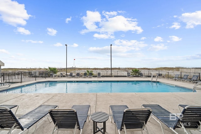 community pool with a patio and fence