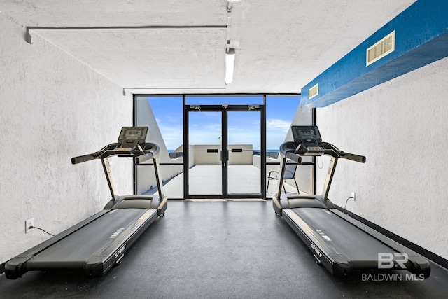 workout room with visible vents, a wall of windows, and a textured wall