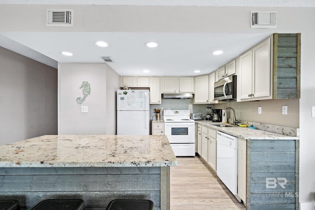 kitchen with white appliances, a sink, visible vents, and under cabinet range hood