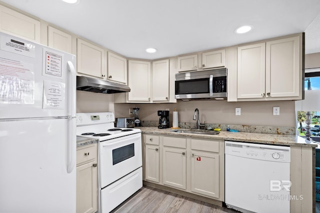 kitchen featuring white appliances, a sink, light stone countertops, and under cabinet range hood