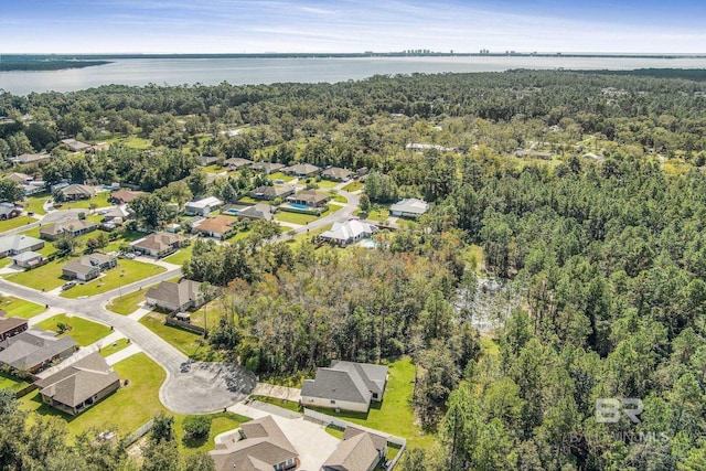 drone / aerial view with a view of trees, a water view, and a residential view