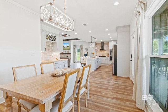 dining space with crown molding and light hardwood / wood-style flooring