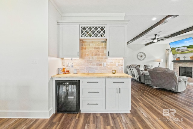 bar featuring wine cooler, dark hardwood / wood-style flooring, ceiling fan, a brick fireplace, and wooden counters