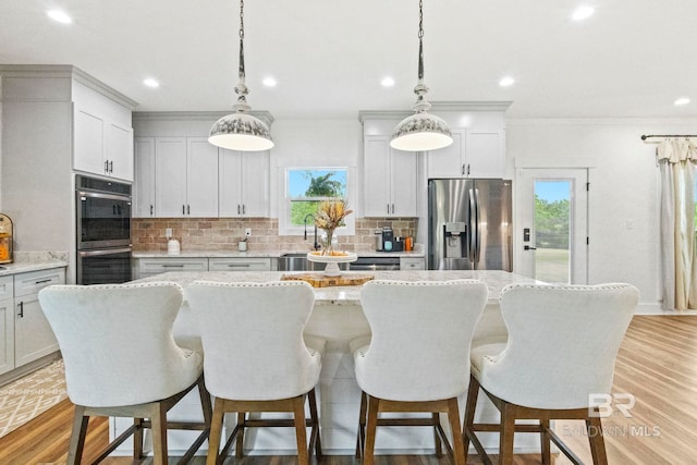 kitchen with plenty of natural light, stainless steel appliances, a center island, and decorative light fixtures