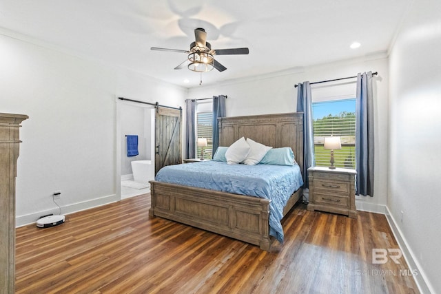 bedroom featuring dark wood-type flooring, ensuite bath, ornamental molding, a barn door, and ceiling fan