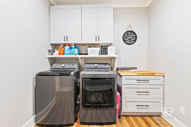 laundry area with cabinets, washer and clothes dryer, and light hardwood / wood-style flooring