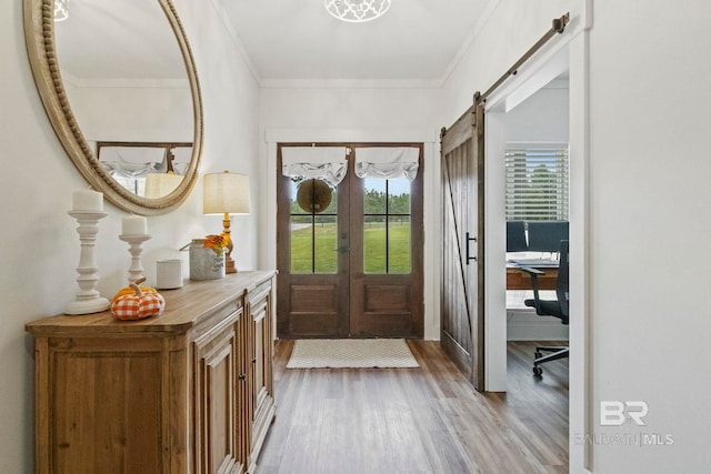 entrance foyer featuring a barn door, hardwood / wood-style flooring, crown molding, and a healthy amount of sunlight