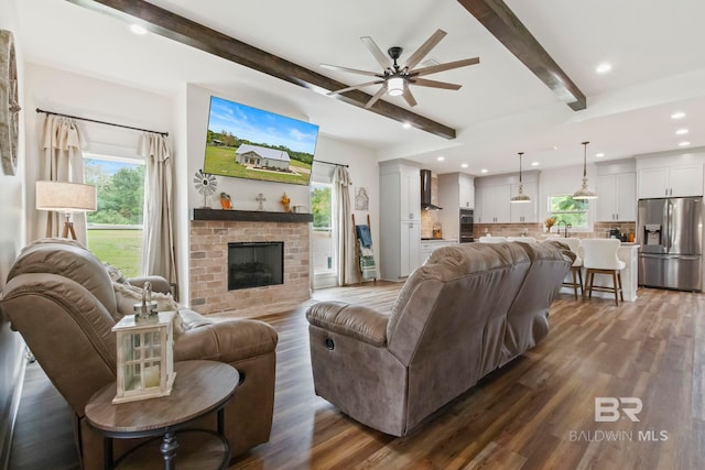 living room with a fireplace, dark wood-type flooring, beam ceiling, and ceiling fan