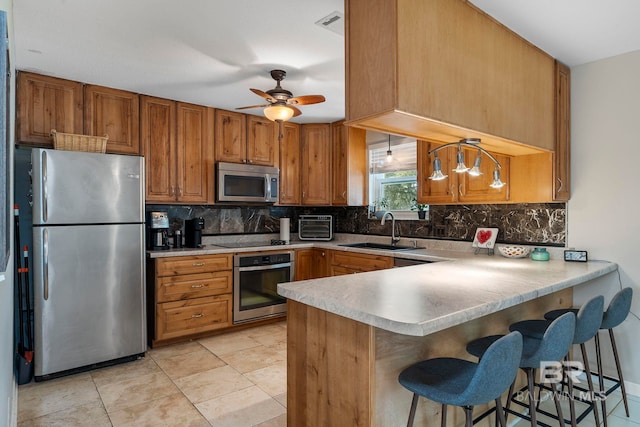 kitchen featuring sink, appliances with stainless steel finishes, backsplash, decorative light fixtures, and kitchen peninsula