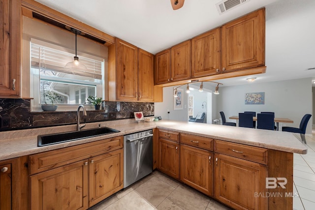 kitchen featuring pendant lighting, sink, decorative backsplash, stainless steel dishwasher, and kitchen peninsula