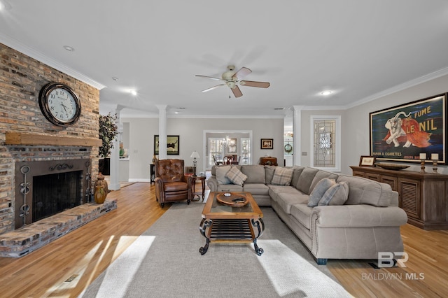 22649 Alice Ln, Fairhope, AL 36532 - living area featuring light wood finished floors, a brick fireplace, crown molding, and decorative columns