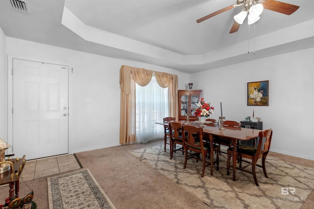 tiled dining room featuring a raised ceiling and ceiling fan