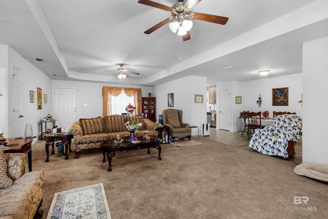 carpeted living room featuring a tray ceiling and ceiling fan