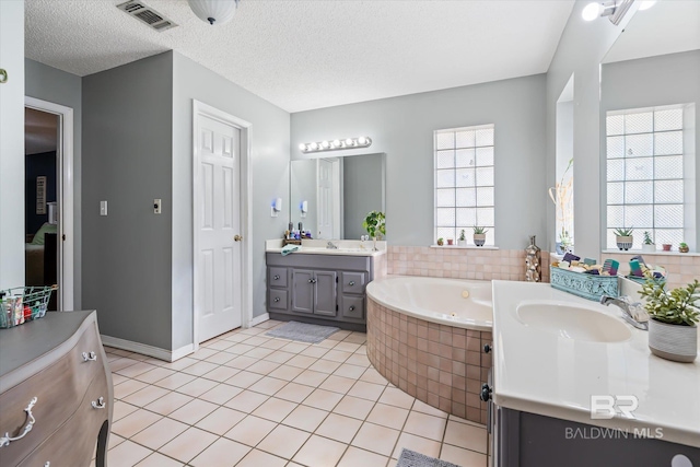 full bath featuring visible vents, a textured ceiling, a whirlpool tub, and a sink