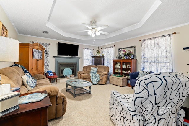 carpeted living area featuring visible vents, ceiling fan, a tray ceiling, ornamental molding, and a textured ceiling